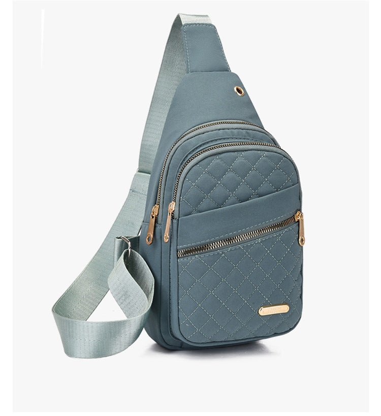 Blue quilted crossbody bag with gold zippers on a white background