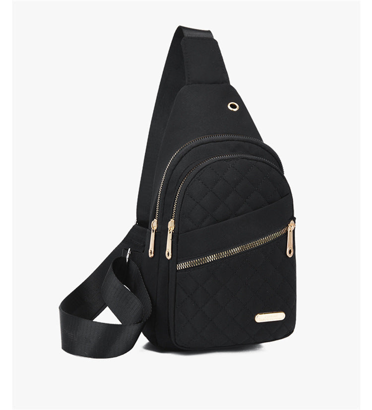 Black crossbody bag with gold zippers on a light gray background